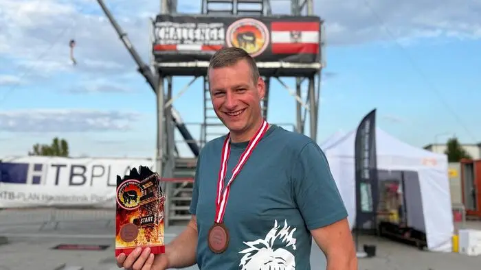 Ein Mann mit einer Medaille um den Hals und einer Trophäe in der Hand