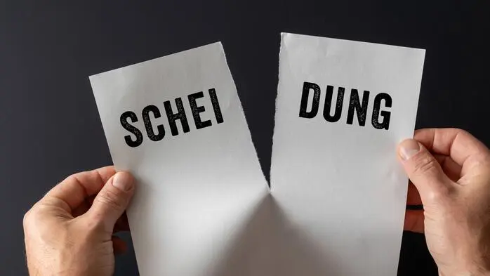 Zettel mit dem Wort „Scheidung“ wird auseinandergerissen.