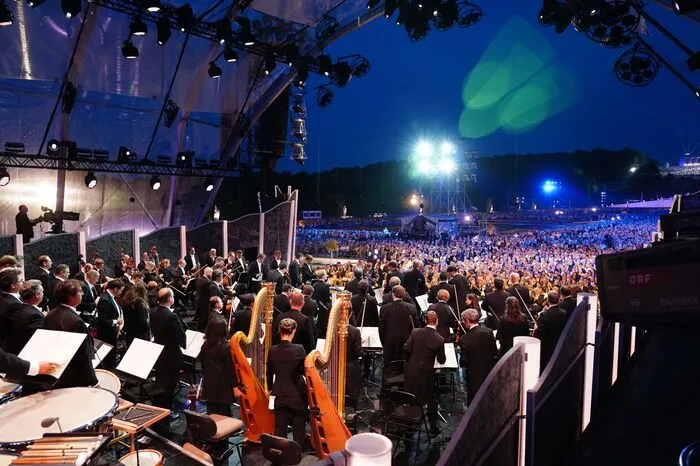 Schloss Schönbrunn, das seit der Drehung der Bühne nun als direkte Kulisse dient, erstrahlt im Gang des Abends in allen denkbaren Bonbonfarben und Netrebko erscheint in Glamourroben zwischen "Dallas", Zarenball und Montserrat Caballe.