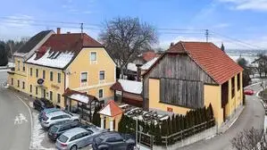Ein gelber Gasthof auf der linken Seite und rechts ein alter Stadel