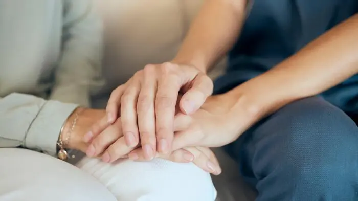 Themenbild: Frau hält die Hände einer älteren Dame