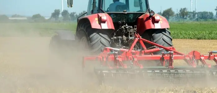 Traktor wirbelt Staub auf einem trockenen Feld auf