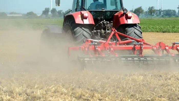 Traktor wirbelt Staub auf einem trockenen Feld auf