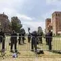 Police retrieve their helmets and riot gear laying next to steel barriers set up outside Royce Hall at the UCLA campus in Los Angeles on Friday, May 3, 2024. More than 200 people were taken into custody at the university early Thursday, after hundreds of protesters defied orders to leave, some forming human chains as police fired flash-bangs to break up the crowds. (AP Photo/Damian Dovarganes)