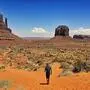 Ein Mann im Monument Valley in Arizona, blauer Himmel, die Erde ist fast orange, im Hintergrund typische Felsformationen | „Zählt die USA als ein Land?“, fragt sich Mario Silly. Hier spaziert er durch das Monument Valley in Arizona