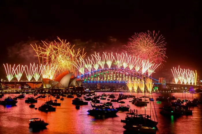 Fireworks explode over the Sydney Harbour Bridge and Sydney Opera House (L) during New Year's Eve celebrations in Sydney on January 1, 2024. (Photo by Izhar KHAN / AFP)
