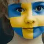 Portrait of a child with a painted Sweden flag on her face, closeup.