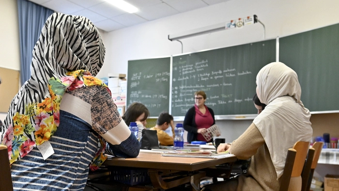 Blick in ein Klassenzimmer, in dem zwei Mädchen mit Kopftüchern zu sehen sind