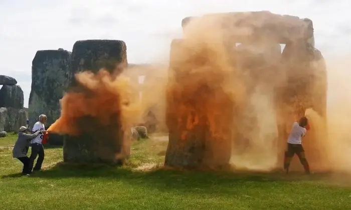 An image grab from a video released by the Just Stop Oil climate campaign group shows activists spraying an orange substance at Stonehenge in Wiltshire, southwest England, on June 19, 2024. UK police said officers had arrested two people after environmental activists sprayed an orange substance on Stonehenge, the renowned prehistoric UNESCO World Heritage Site in southwest England. (Photo by Handout / Just Stop Oil / AFP) / RESTRICTED TO EDITORIAL USE - MANDATORY CREDIT 