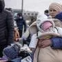 TOPSHOT - A woman holds a baby as Ukrainian citizens arrive at the Medyka pedestrian border crossing fleeing the conflict in their country, in eastern Poland on February 27, 2022. - As Ukraine braces for a feared Russian invasion, its EU member neighbours are making preparations for a possible influx of hundreds of thousands or even millions of refugees fleeing military action. (Photo by Wojtek RADWANSKI / AFP)