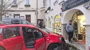 Rotes Auto mit demolierter Schnauze vor eingefahrenem Juwelierschaufenster