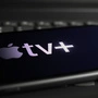 Viersen, Germany - March 1. 2021: Closeup of smartphone screen with logo lettering of online streaming service apple tv on computer keyboard