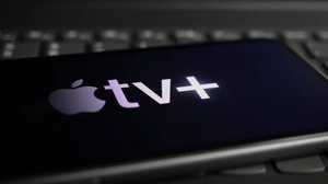 Viersen, Germany - March 1. 2021: Closeup of smartphone screen with logo lettering of online streaming service apple tv on computer keyboard