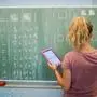 ARCHIV - 17.08.2016, Niedersachsen, Hannover: Eine junge Lehrerin schreibt an eine Schultafel im Mathematikunterricht einer 8. Klasse an einer Integrierten Gesamtschule und blickt dabei auf einen Tablet-Computer. (zu dpa: «Lehrerbildung soll besser auf Schulalltag vorbereiten») Foto: Julian Stratenschulte/dpa +++ dpa-Bildfunk +++