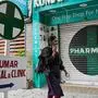 A woman walks past a closed pharmacy in Bengaluru on August 6, 2025. Dozens of economies around the world including the European Union and India are expected to face higher US tariffs on August 7, as Trump’s long-threatened “reciprocal” duties, over trade practices Washington deem unfair, take effect. (Photo by Idrees MOHAMMED / AFP)