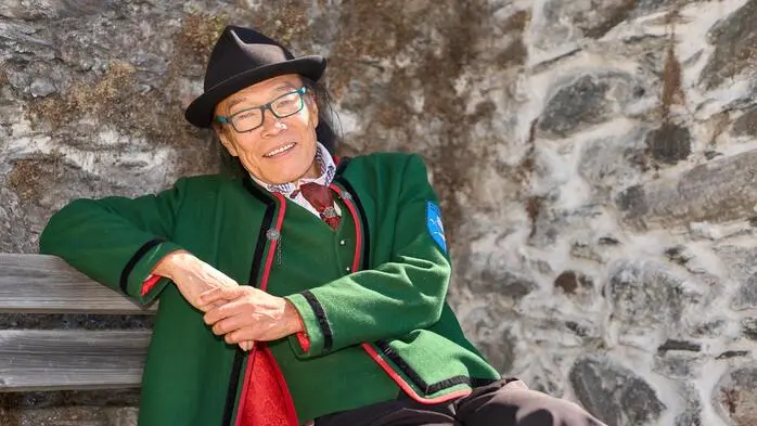 Man sieht einen Japaner in traditioneller Kärntner Kleidung in die Kamera lächeln