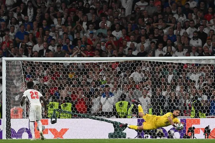 Italy's goalkeeper Gianluigi Donnarumma saves a decisive penalty by England's midfielder Bukayo Saka in the shootout during the UEFA EURO 2020 final football match between Italy and England at the Wembley Stadium in London on July 11, 2021. (Photo by Paul ELLIS / POOL / AFP)