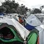 People walk among the tents in the Vial refugee camp, on the Greek island of Chios on December 11, 2019. - The Vial camp on the island of Chios has only 1,000 places, but nearly 5,000 asylum seekers currently live there in unsanitary conditions and many camps situated in the nearby olive groove are without toilets, bathrooms, electricity and water. In addition to lack of hygiene, "insecurity, especially at night, is often mentioned by women," reports the Office of the High Commissioner for Refugees (UNHCR). In the improvised camp, single men of various nationalities live together, adolescent girls or elderly or pregnant women. The NGO Human Rights Watch recently sounded the alarm, calling on the Greek government to "act immediately to ensure safe and humane conditions for women and girls" in camps on the Greek islands. (Photo by LOUISA GOULIAMAKI / AFP)