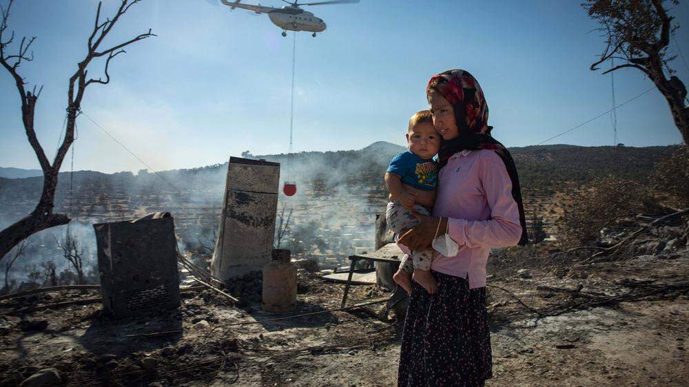 Eine Frau mit Kind steht im niedergebrannten Lager Moria auf der griechischen Insel Lesbos