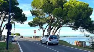 Straße mit Auto und dahinter die Adria | Gefährliches Miteinander von Radlern und Autofahrern auf ganz engem Raum