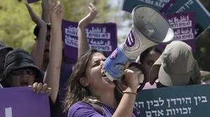 An Israeli activist leads chants during a protest against plans by Prime Minister Benjamin Netanyahu's government to overhaul the judicial system, in the West Bank settlement of Kdumim, the home of right-wing lawmaker and Minister of Finance Bezalel Smotrich, Friday, July 28, 2023. While many lawmakers' homes have been the site of anti-overhaul protests, this was a rare protest inside an Israeli settlement. (AP Photo/Maya Alleruzzo)