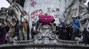 A man holds a heart-shaped cushion reading "Macron I hate you with all my heart" during an election night rally following the first results of the second round of France's legislative election at Republique Square in Paris on July 7, 2024. A broad left-wing coalition was leading a tight French legislative election, ahead of both President's centrists and the far right with no group winning an absolute majority, projections showed. (Photo by Olympia DE MAISMONT / AFP)