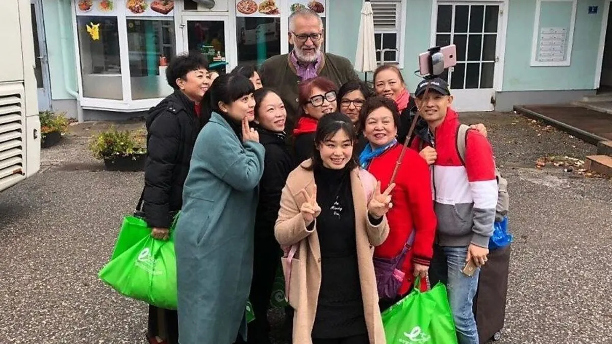 Aufgrund seiner Größe ein beliebtes Fotomotiv: Der 2,02 Meter große Hotel-Besitzer Peter Mosgan inmitten chinesischer Touristen 