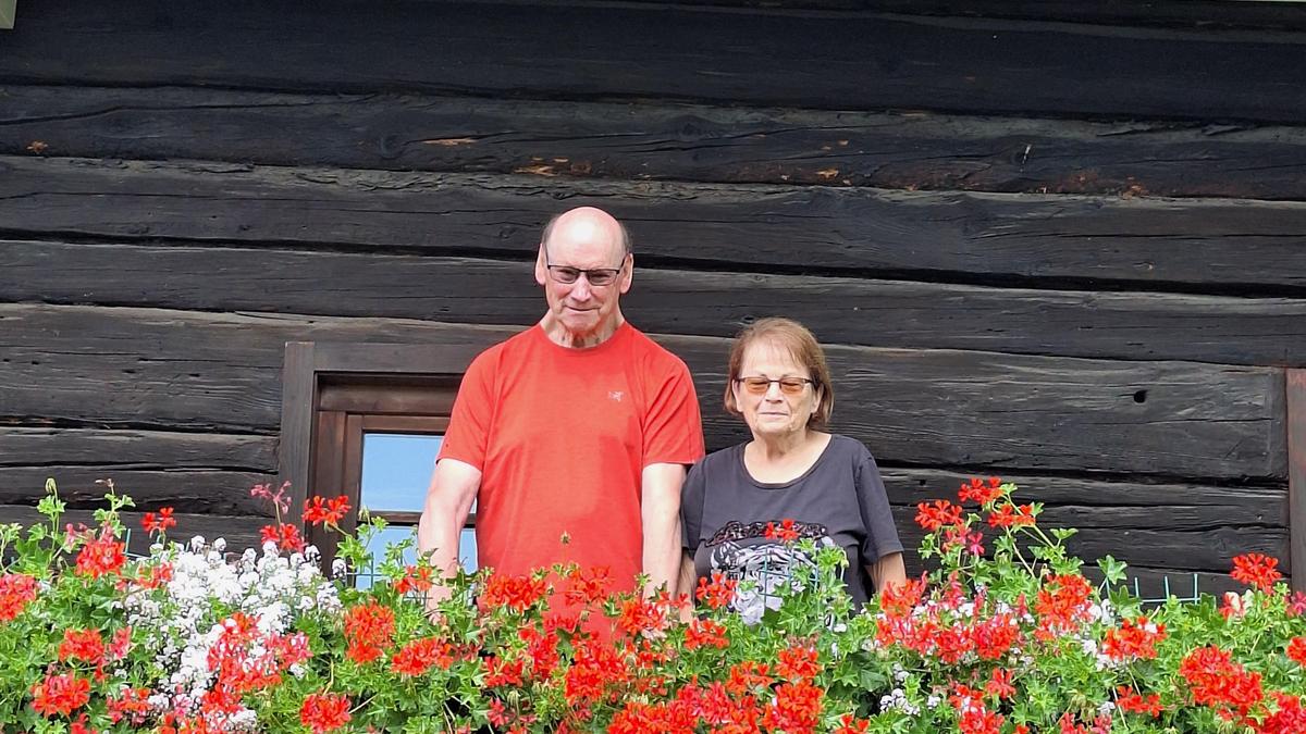 Familie Brunner aus Sonnwiesen auf dem Balkon des alten Bauernhauses, das sie mit Hängegeranien verschönern