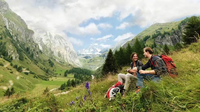 Zwei Wanderer sitzen in einer Wisse in den Bergen