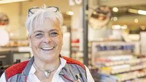 Frau mit weißen kurzen Haaren und Brille im Haar lacht in die Kamera