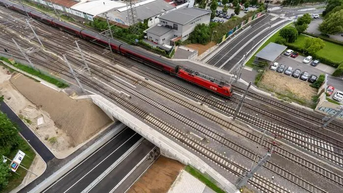 Die Eisenbahnbrücke Peter-Tunner-Gasse aus der Luftperspektive, wie gerade ein Zug drüberfährt