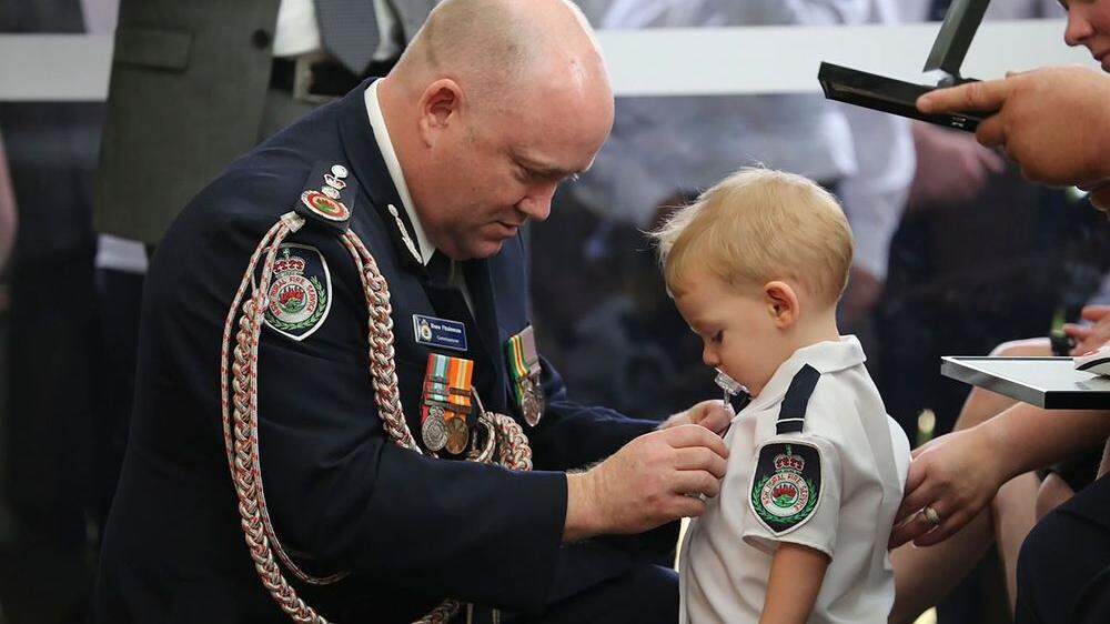 Feuerwehrchef von New South Wales, Shane Fitzsimmons heftet Harvey Keaton eine Auszeichnung an - für den mutigen Einsatz seines Vaters Geoffrey Keaton 