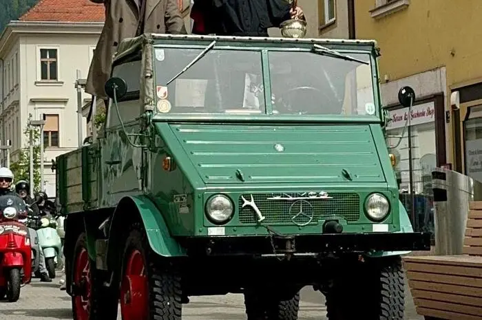 Danach ging es im gemeinsamen Konvoi zur Stadtpfarrkirche Sankt Xaver. Am Kirchplatz wurde Stadtpfarrer Markus J. Plöpst und Stadtrat Johannes Gsaxner auf einem Mercedes UNIMOG aufgenommen, um mit rund 100 Fahrzeugen die gemeinsame Fahrt Richtung Hauptplatz fortzusetzen