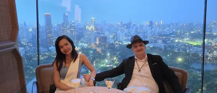 Ein europäischer Mann und eine thailändische Frau vor einer Skyline bei Nacht