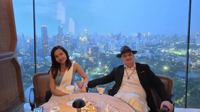 Ein europäischer Mann und eine thailändische Frau vor einer Skyline bei Nacht