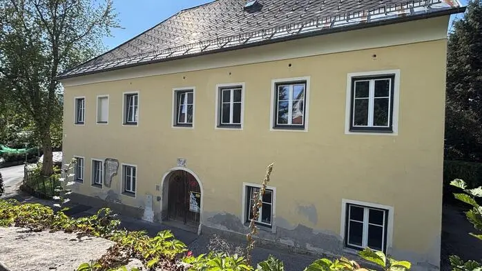 Ein gelbes älsteres Haus mit weißen Fenstern