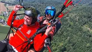 Zwei Personen hoch über dem Boden im Tandemflug am Gleitschirm