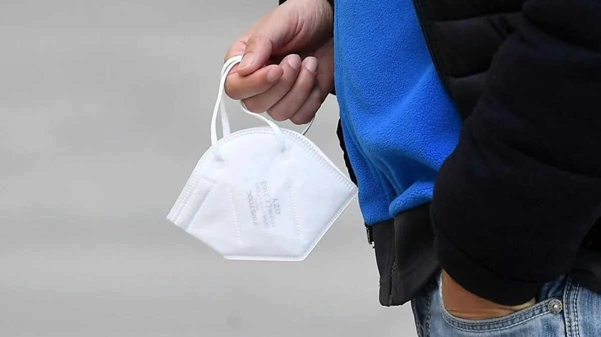 Mann hält Maske in der Hand