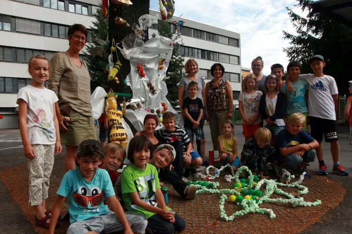 Die Lehrerinnen der Reformpädagogischen Mehrstufenklassen mit Künstlerin Černe (6. von links) und einigen Kindern vor dem kunstvoll gestalteten Baum im Schulhof.