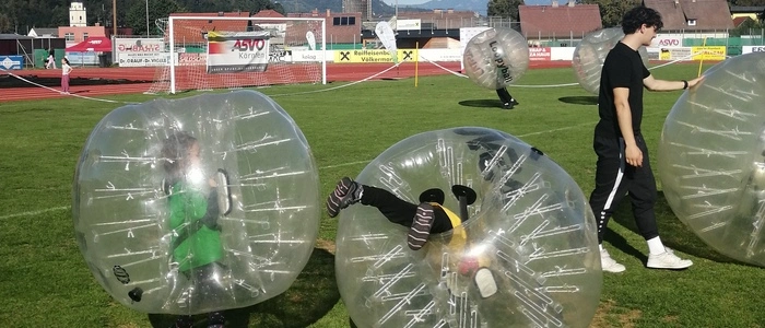 Zu sehen sind Kinder, die in einem durchsichtigen Plastikball (Loopy-Ball) stecken