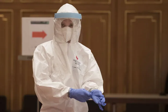 Die Personen, die die Abstrichabnahme durchführen, sind in Schutzkleidung und tragen auch mehrere Schichten Handschuhe.