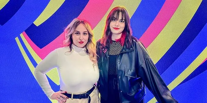 Teya & Salena vor dem Logo des ESC 2023, wo die ukrainischen Faben integriert sind: Österreichs Duo hat tolle Wettquoten.