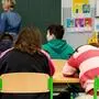 Man sieht eine Lehrerin an der Tafel und drei Schüler