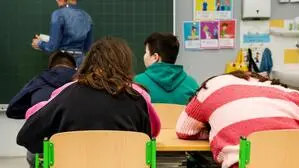Man sieht eine Lehrerin an der Tafel und drei Schüler