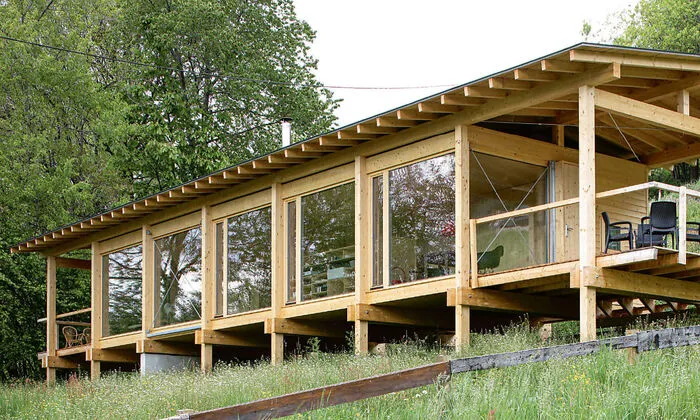 Der Holzbau berührt den Boden nur punktuell und ist durch ein leichtes, schwebendes Satteldach gut geschützt