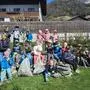 Mehrere Kinder sitzen auf Steinen und präsentieren stolz die vollen Müllsäcke