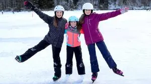 Drei Kinder in Eislauf-Schuhen lachen in die Kamera | Eislauffans kommen bereits jetzt am Goggausee auf ihre Kosten