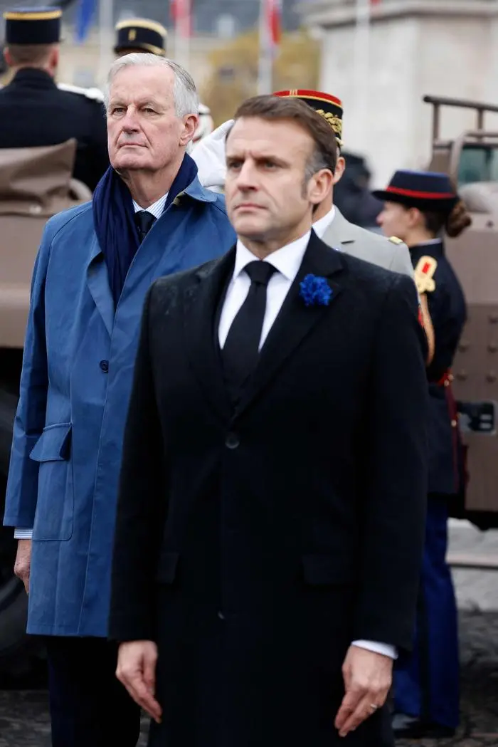 France's President Emmanuel Macron (R) and France's Prime Minister Michel Barnier stand at attention during commemorations marking the 106th anniversary of the November 11, 1918, Armistice, ending World War I (WWI), in Paris, on November 11, 2024. (Photo by Ludovic MARIN / POOL / AFP)