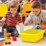 Two cute little boys playing with toy railway in kindergarten