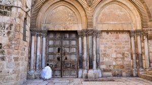 Ein Pilger kniet vor dem verschlossenen Tor der Grabeskirche in Jerusalem
